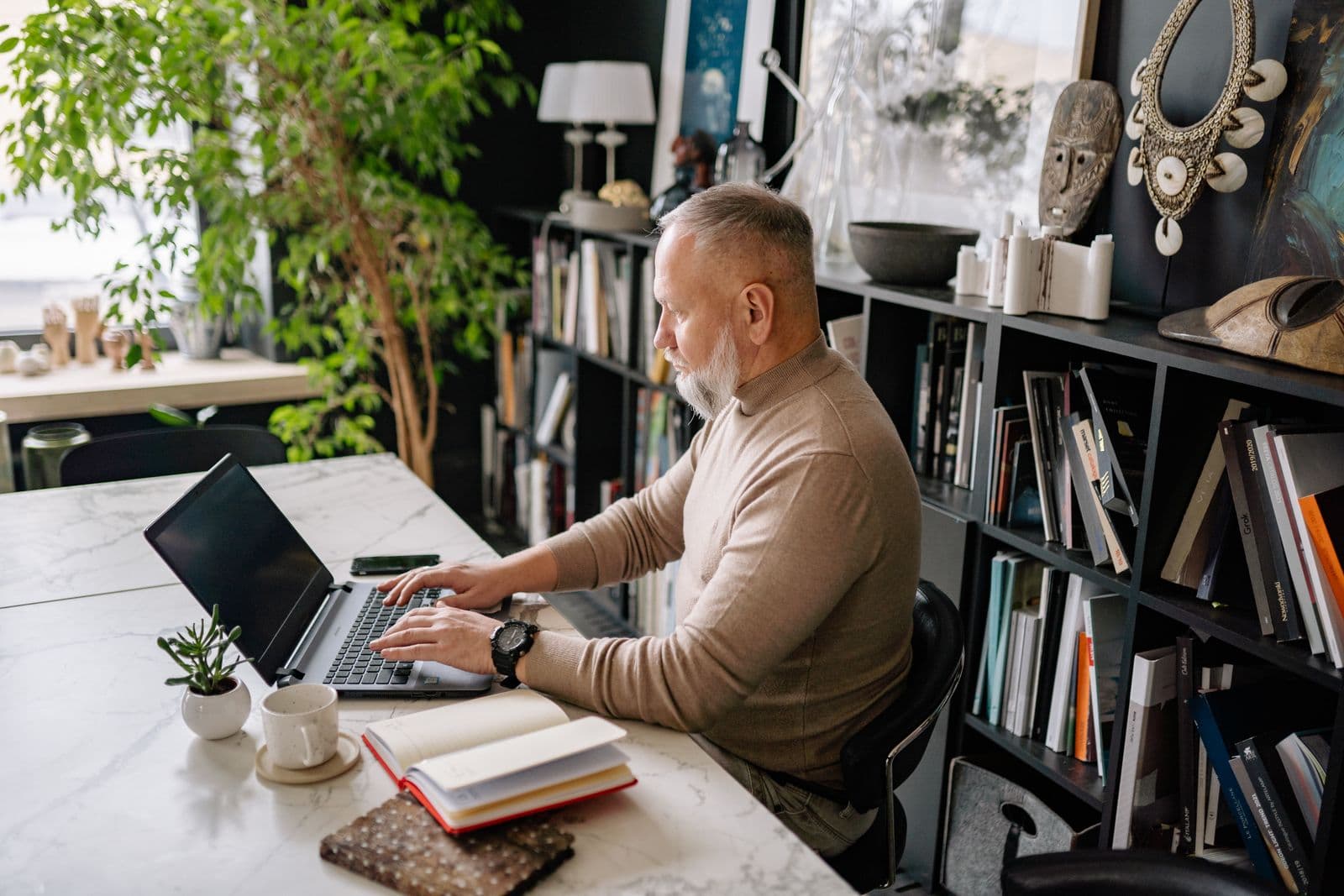 A man in his sixties reviewing his retirement plan on a laptop at home